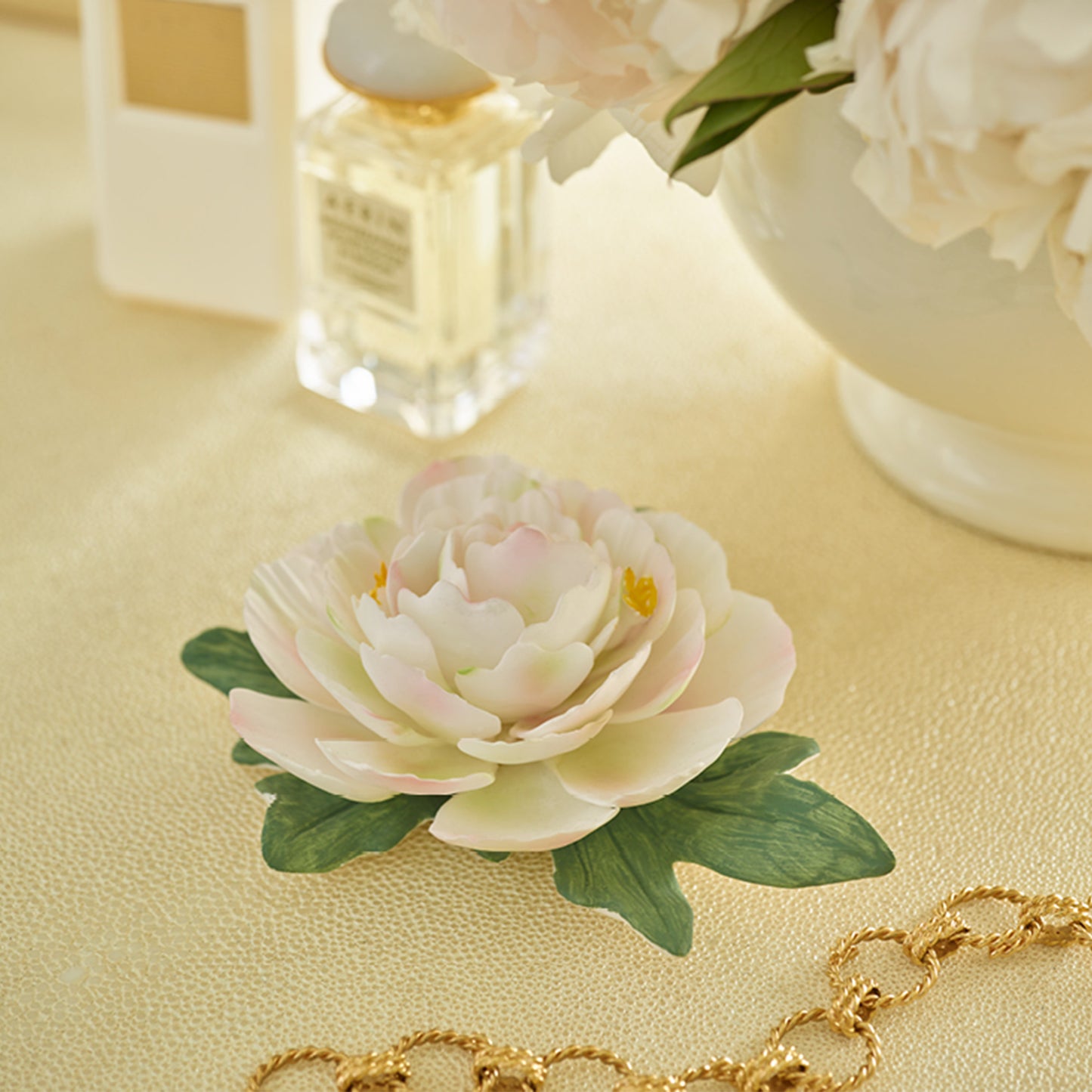Decorative porcelain flower with green leaves against a light background
