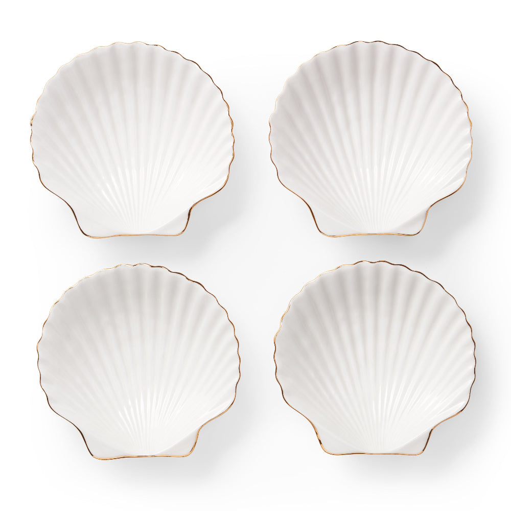 Four white shell-shaped plates with gold edges on a white background