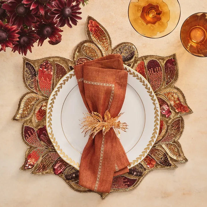 Decorative table setting with a patterned placemat, white plate, and brown napkin.