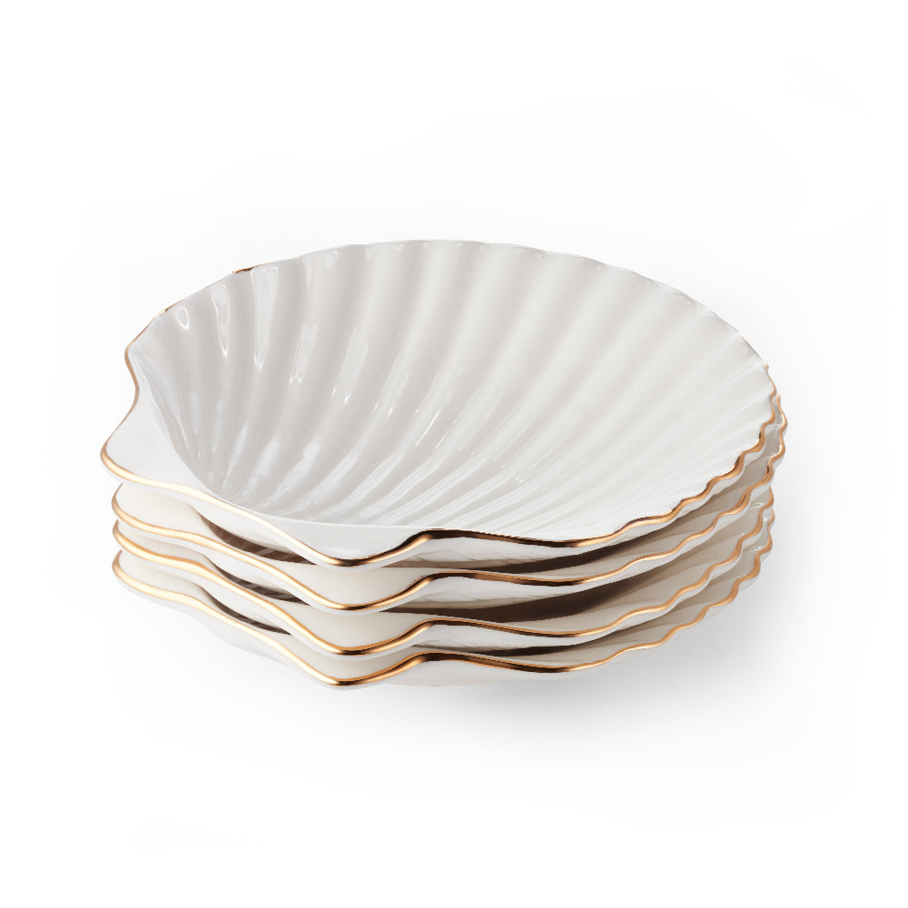 Set of four white ceramic plates with scalloped edges and gold trim on a white background