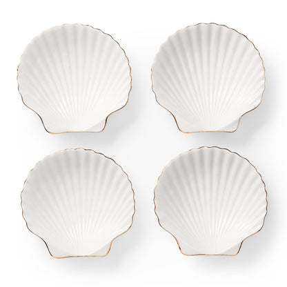 Four white shell-shaped plates with gold edges on a white background