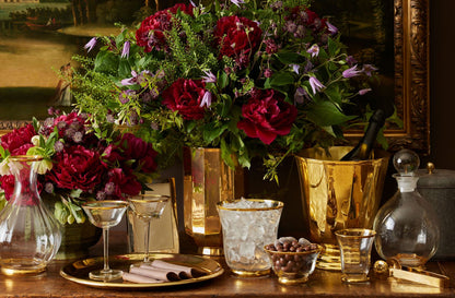 Decorative table setting with flowers, glasses, and a ice bucket on a wooden surface.