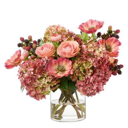 Along The Way by Diane James Home is a vibrant artificial flower bouquet featuring salmon ranunculus, pink hydrangeas, coral poppies, and raspberries arranged in a clear glass vase on a white background.