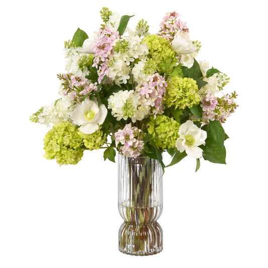 Bouquet of faux lilacs, snowball viburnum and anemones in a fluted clear vase on a white background