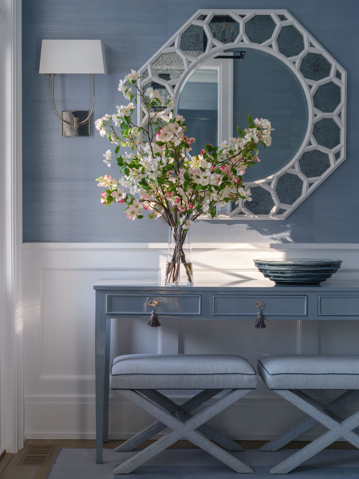 Console table with arrangement and a decorative mirror against a blue wall.
