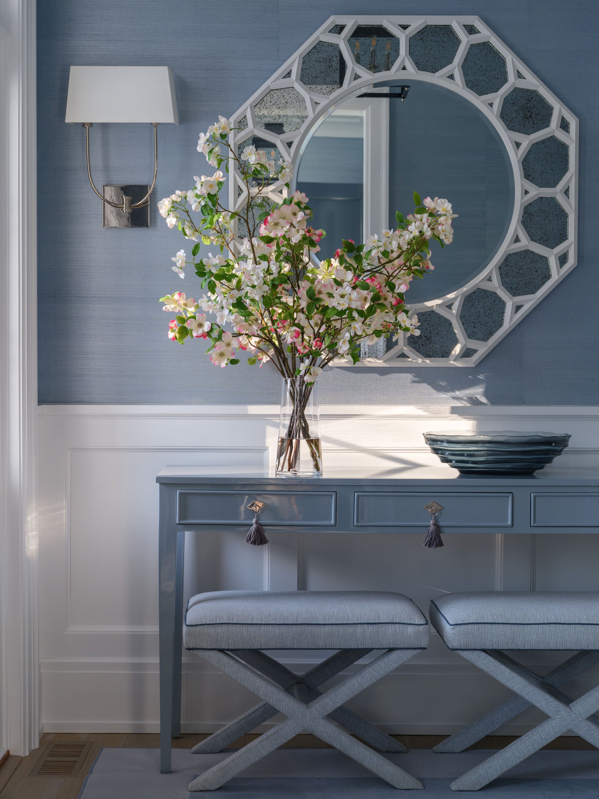 Console table with arrangement and a decorative mirror against a blue wall.