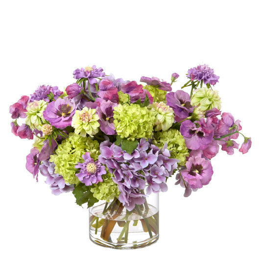 Bouquet of faux purple and green flowers in a clear vase by Diane James Home on a white background