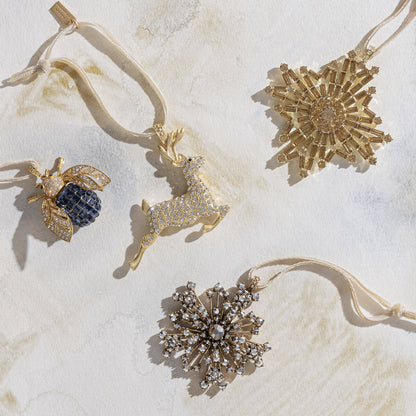 A selection of Joanna Buchanan holiday ornaments featuring stars, reindeer and bug