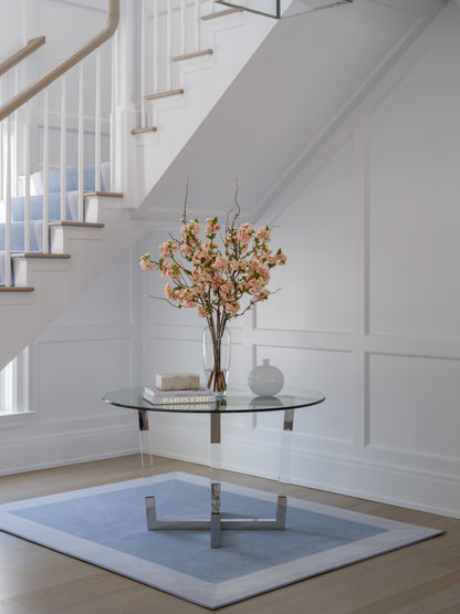 Modern interior with a glass table, vase of flowers by Diane James Home, and staircase in the background.