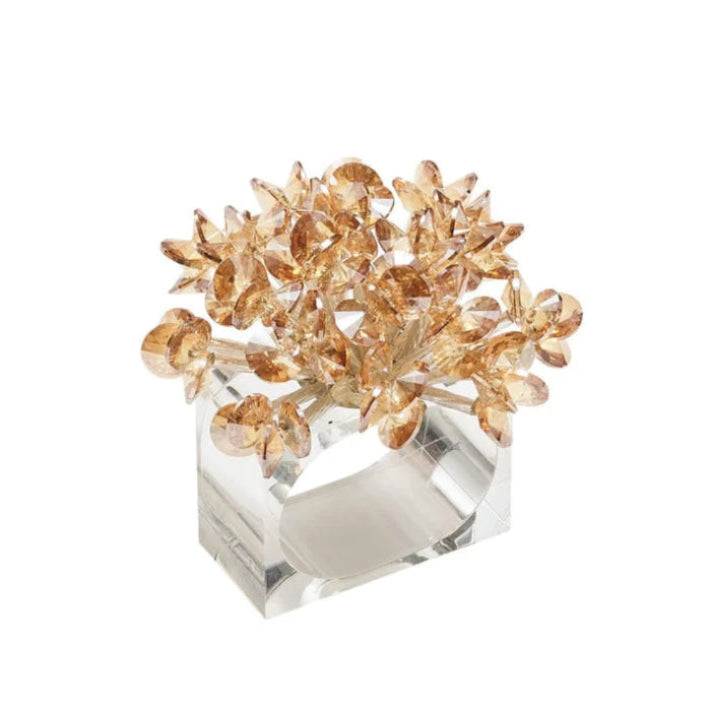 A crystal and gold floral napkin ring featuring a cluster of faceted gold leaves on a clear lucite base, shown against a plain white background.