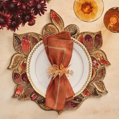 Decorative table setting with a patterned placemat, white plate, and brown napkin.