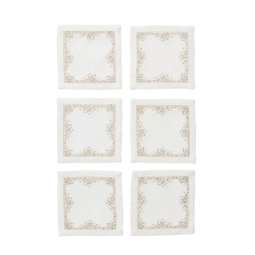 Six square white napkins with delicate gold pin dot embroidery along the borders, arranged in a two-column grid on a solid white background.