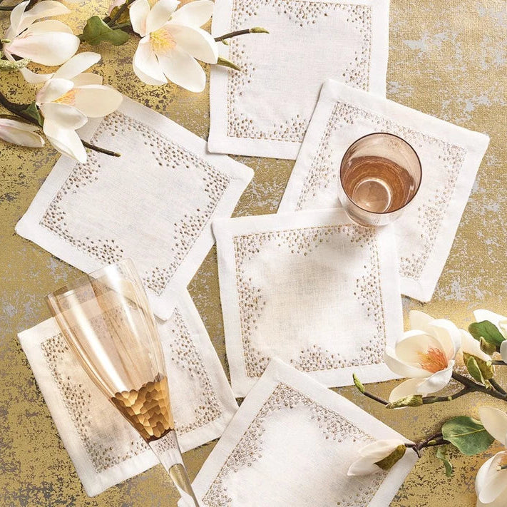 Decorative white napkins with pin dot patterns on a textured surface with flowers.