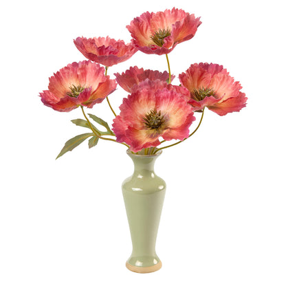 A bouquet of artificial coral poppies with yellow centers and green leaves, arranged in a glossy pale green ceramic vase on a white background.
