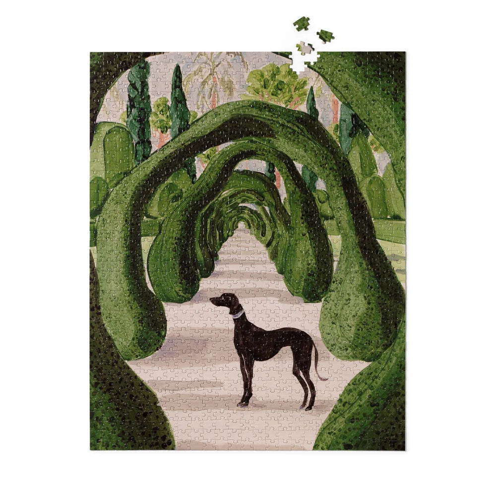 A jigsaw puzzle featuring a stylized garden scene with green topiary-like arches framing a pale path and a black dog standing in the foreground, shown against a white background with a few loose puzzle pieces above.