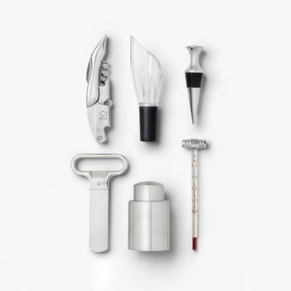 A set of stainless steel wine accessories arranged on a light gray background, including a corkscrew, a glass stopper, a bottle aerator, a bottle opener, a bottle stopper with black accent, and a wine thermometer.