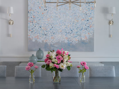 Faux floral arrangement by Diane James Home on a dining table with a wall painting in the background